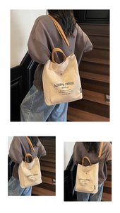 Detail of beige canvas tote bag with brown handles and adjustable crossbody strap