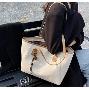 Detail of off-white lychee grain tote bag with brown straps and heart pendant