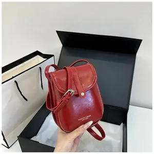 Detail view of red patent leather mini crossbody bag with snap button in gift box