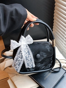 Chic black velvet handbag with a white lace bow detail and gold hardware accents