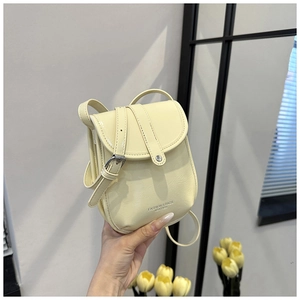 Detail of a light yellow leather crossbody bag with FASHION & BAGS embossed logo text