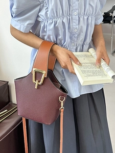 Secchiello in pelle bordeaux e arancione con fibbia dorata indossato da modella