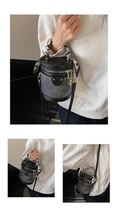 Detail of grey bucket bag with black leather trim and silk scarf handle decoration