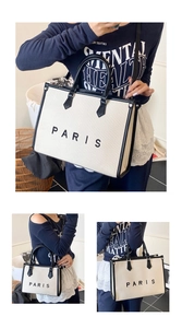 Detail of canvas tote bag showing black leather trim, Paris lettering and crossbody strap