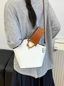 Borsa a secchiello bianca minimalista da donna con tracolla marrone portata a spalla