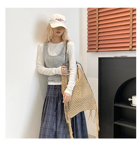 Détail du sac cabas en paille beige tissé main avec de longues franges et un motif ajouré