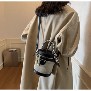 Detail of grey canvas bucket bag with leather trim and silk scarf handle on model