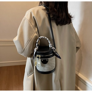 Detail of grey canvas bucket bag with black leather trim and decorative silk scarf wrap