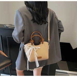 Détail du sac beige avec poignées marron nouées et nœud en dentelle avec perle