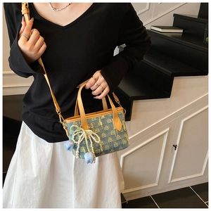 Dettaglio borsa in denim con fiocco di perle e ciondolo a tulipano blu sulla tracolla