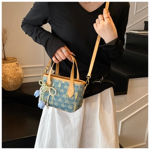 Dettaglio della borsa tote in denim con ciondolo floreale e fiocco di pizzo