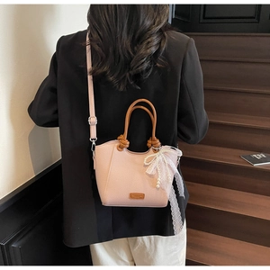 Détail du sac cabas en cuir grainé rose avec nœud élégant en dentelle et perles