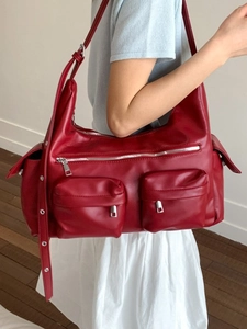 Red moto-style leather tote bag with silver zippers and adjustable strap worn on shoulder
