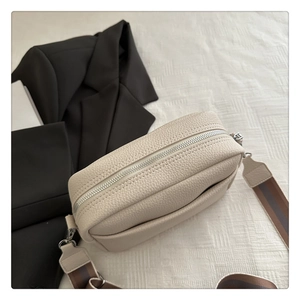 Detail of cream lychee texture crossbody camera bag with striped wide fabric strap