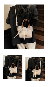 Détail du cabas beige avec nœud en dentelle, perle et poignée circulaire marron