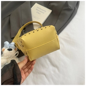 Détails des motifs ajourés et de la texture cuir grainé sur ce sac seau jaune élégant