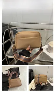 Close-up of brown litchi pattern leather crossbody bag with striped wide shoulder strap