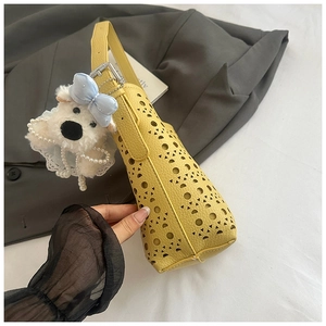 Détail du sac jaune ajouré au laser avec un adorable pendentif chiot en peluche