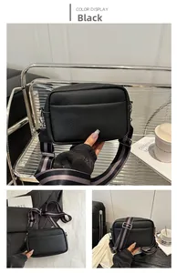 Detail view of black pebble leather crossbody bag with a wide adjustable textile strap