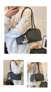 Détail du sac Boston gris foncé texturé avec breloque étoile et bandoulière