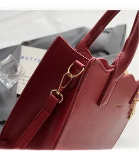 Detailaufnahme einer dunkelroten Lederhandtasche mit goldenen Beschlägen und feiner Naht