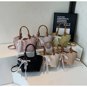 Détail de six sacs cabas en cuir colorés avec pendentifs perles et nœuds en dentelle