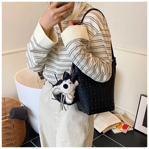 Détail du sac seau noir ajouré avec pendentif chiot en peluche blanche et chaîne perle