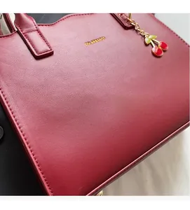 Detail der roten Brauthandtasche mit Litschi-Lederstruktur und goldenem Markenlogo