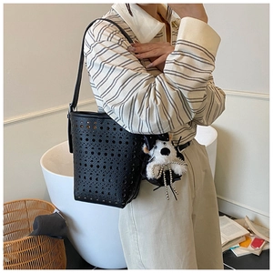 Détail du sac seau noir découpé au laser avec un joli pendentif chiot en peluche blanche