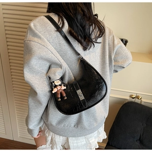Detail of black pleated leather crescent bag with silver square buckle and doll charm