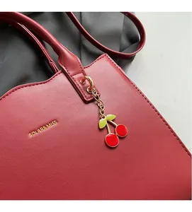 Nahaufnahme der roten Brauthandtasche aus Leder mit Kirsch-Anhänger und Markenlogo