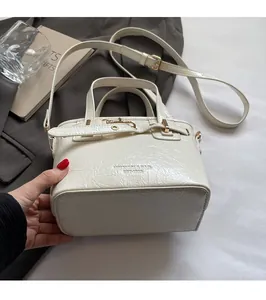 Close-up of white pleated crossbody bag featuring MINXIOU logo and metal buckle details