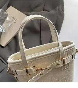 Close-up of cream textured tote bag with glossy finish and gold metal hardware