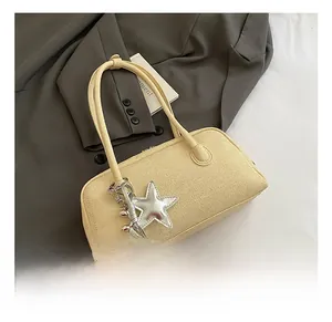 Détails d'un sac Boston jaune à texture tissée avec un grand pendentif étoile argenté