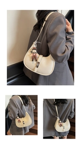 Close-up of cream crescent bag featuring silver twist lock and a cute girl charm detail