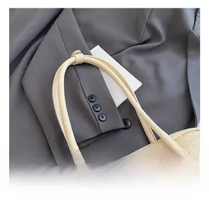 Détail de la texture tressée du sac Boston crème avec poignée souple et finitions chics