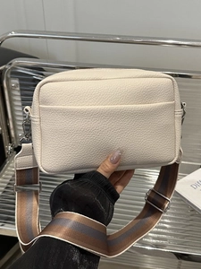 Creamy white lychee grain leather crossbody bag with a colorful striped fabric strap