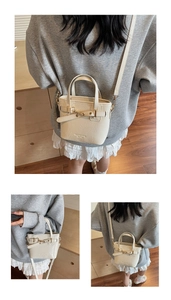 Detail of cream white leather tote bag featuring gold hardware and removable shoulder strap