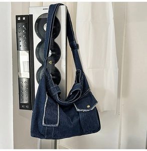 Détail du sac cabas en denim bleu foncé avec deux poches avant et bandoulière réglable