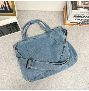 Détail du grand cabas en jean bleu avec bandoulière réglable sur un bureau moderne