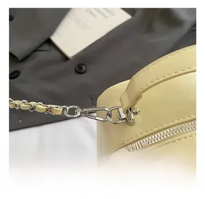 Detail des hochwertigen Silberhakens und der geflochtenen Kette an einer cremefarbenen Tasche