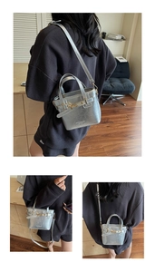 Detailed close-up of a silver textured handbag with a gold lock and adjustable strap