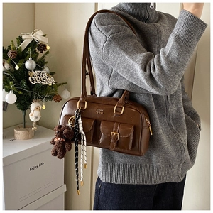 Detail einer Retro-Schultertasche aus dunkelbraunem Leder mit doppelten Schnallentaschen