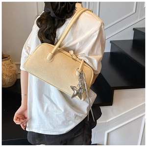 Détail du sac Boston beige tressé avec breloque étoile argentée et pompon élégant