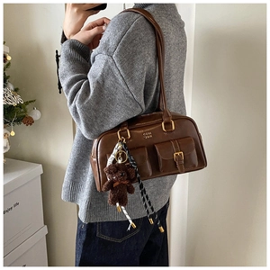 Detail der braunen Retro-Schultertasche mit Utility-Taschen und Plüschbär-Anhänger