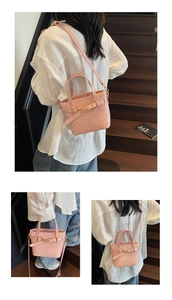 Detail of pink glossy patent leather bucket bag with metal buckle and adjustable strap