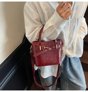 Close-up of retro red bucket bag with crocodile texture and gold metal buckle detail