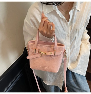 Detail view of pink textured leather bucket bag with gold hardware and brand embossing