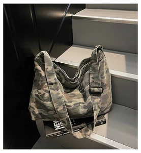 Detail of adjustable black buckle and wide shoulder strap on camouflage canvas tote bag