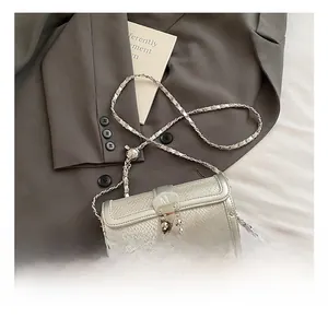 Detail of silver cylinder bag featuring snake pattern texture and silver M buckle